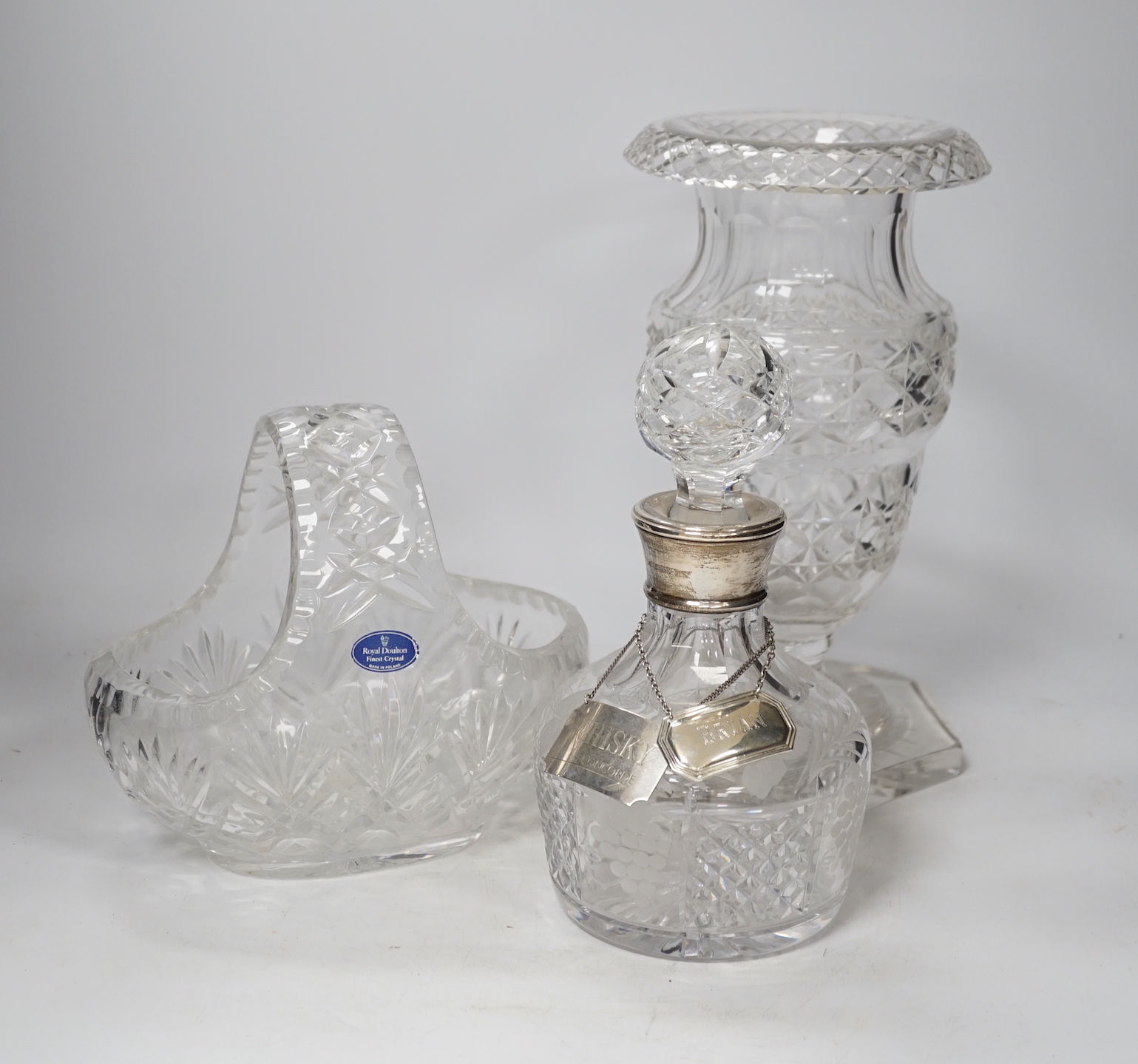 A silver mounted cut glass decanter with silver Concorde label and another label, together with a cut glass urn and a moulded glass basket, urn 28.5cm